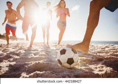 Friends playing football at the beach