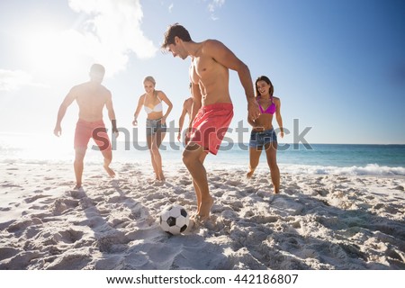 Friends playing football at the beach