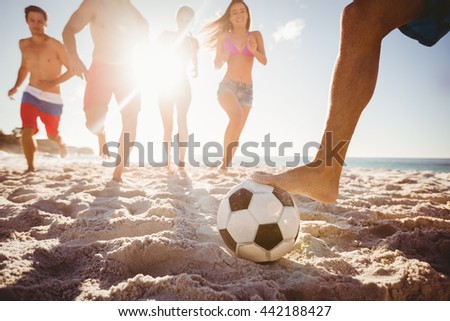 Friends playing football at the beach