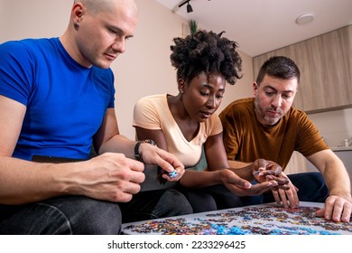Friends playing with jigsaw puzzle at home, on a white wooden table. Putting things together and solving problems. Fun and diversity in friendship. - Shutterstock ID 2233296425