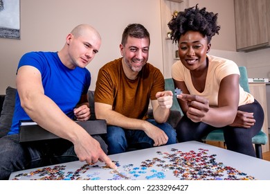 Friends playing with jigsaw puzzle at home, on a white wooden table. Putting things together and solving problems. Fun and diversity in friendship. - Shutterstock ID 2233296427