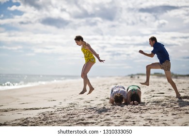 Friends Playing Leapfrog On The Beach