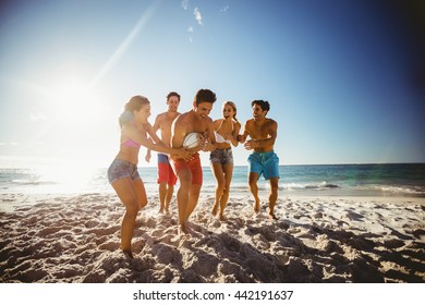 Friends playing rugby at the beach - Powered by Shutterstock