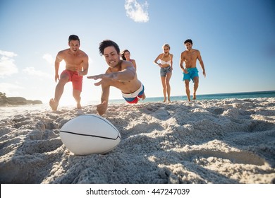 Friends playing rugby at the beach - Powered by Shutterstock