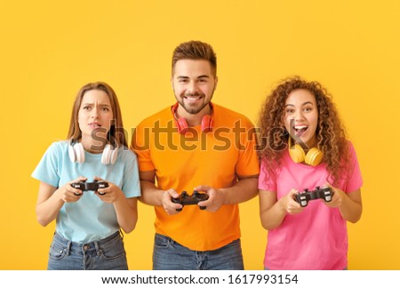 Friends playing video game on color background