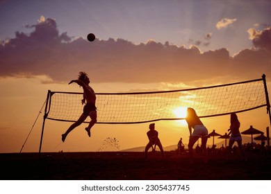 Friends playing volleyball at beach in group, young athletic man jumping hitting ball. Sport, fun, togetherness, lifestyle concept. - Powered by Shutterstock