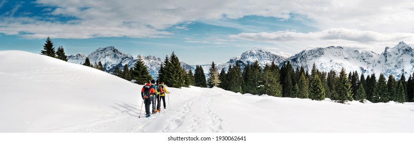Freunde, die Schneeschuhwandern in den schneebedeckten Bergen praktizieren. Dolomiten, Italien. 