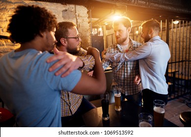 Friends preventing fighting of two angry guys in the bar. - Shutterstock ID 1069513592