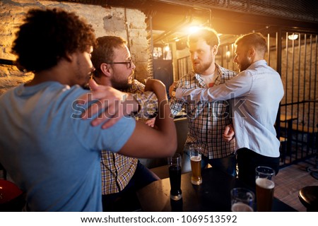 Friends preventing fighting of two angry guys in the bar.