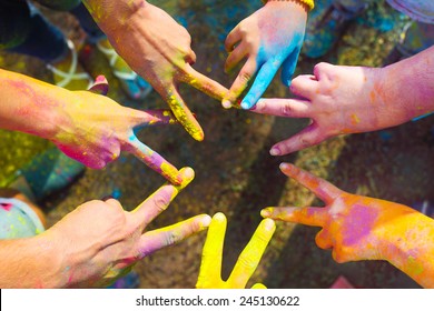 Friends putting their hands together in a sign of unity and teamwork. Holi colors festival. Friendship concept - Powered by Shutterstock