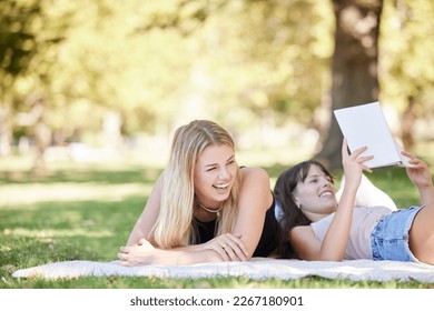 Friends relax in the park, nature and reading with fun on a picnic, young women together with laughing and book. Summer, gen z and female students on vacation, fresh air for happiness and travel