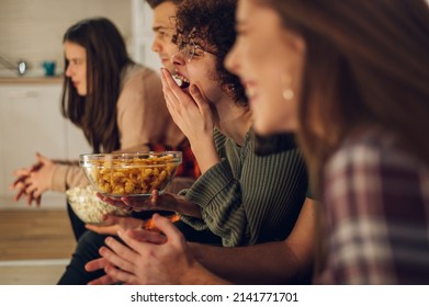 Friends Relaxing Together At Home And Watching Television And Eating Snacks. Watching Interesting Movie At Home. Spending Weekend Together At Home.