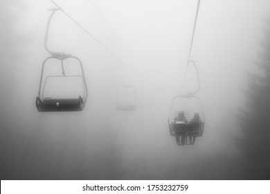 Friends Riding On A Chairlift Through The Misty Woods.