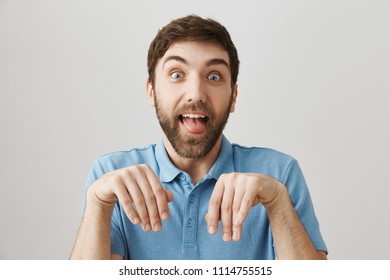 Friends Say His Girlfriend Tamed Him Like Dog. Funny European Boyfriend With Beard Making Dumb Face, Sticking Out Tongue And Standing With Folded Hands Over Gray Wall As If He Is Puppy