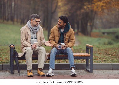 Friends, a senior and a young man sit in the park on a bench and talk in the autumn park. - Powered by Shutterstock