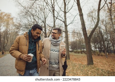 Friends, a senior and a young man walking and talking and drinking coffee together in the autumn park.
 - Powered by Shutterstock