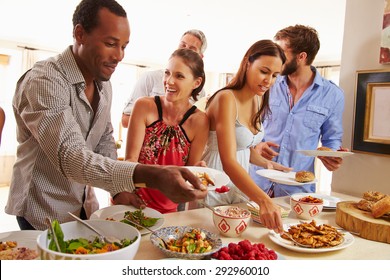 Friends Serving Themselves Food And Talking At Dinner Party