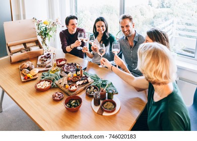 Friends Sitting Around A Table Having Fun With Wine And Food