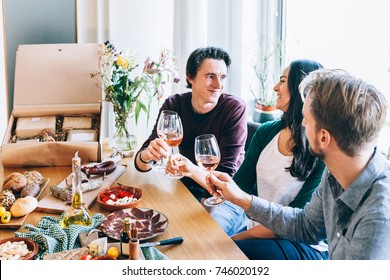 Friends Sitting Around A Table Having Fun With Wine And Food