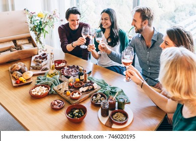 Friends Sitting Around A Table Having Fun With Wine And Food