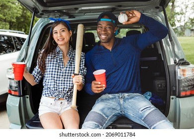 Friends Sitting And Drinking In The Car Boot At A Tailgate Party