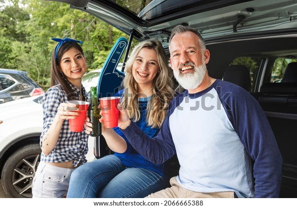 Friends sitting and drinking in the car boot at a\
tailgate party