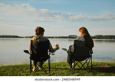 friends are sitting on camping chairs, enjoying a summer and drinking beer with foam with lake view  - Powered by Shutterstock