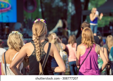 Friends Sitting On The Grass, Enjoying An Outdoors Music, Culture, Community Event, Festival