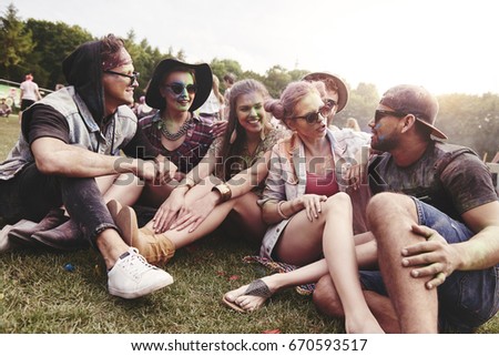 Friends sitting on the grass at music festival 