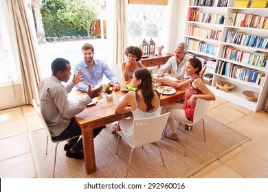 Friends sitting at a table talking during a dinner party - Powered by Shutterstock