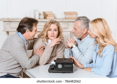 friends sitting at table while using projector on table   