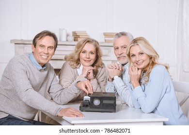 friends sitting at table while using projector on table   