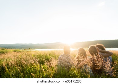 Friends sitting together at lake in summer enjoying sundown and evening mood - Shutterstock ID 635171285