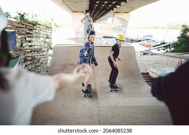 Friends skateboarders doing tricks while rolling on half pipe in skate park. Sports children and outdoor activities in extreme park. Happy kids on skateboards at ramp. Young skateboarders in skatepark