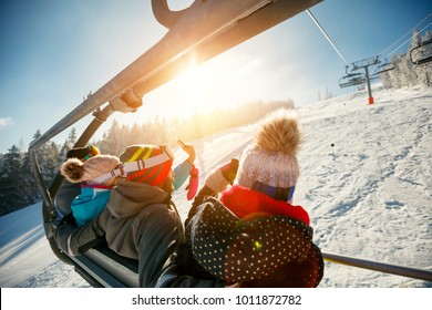 friends skiers and snowboarders on ski lift in the mountain at winter vacations back view - Powered by Shutterstock