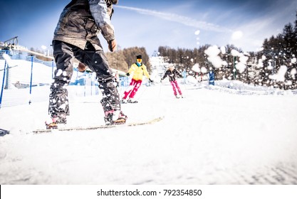 Friends Skiing And Snowboarding On The Snow Tracks