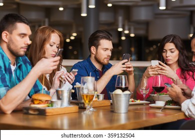 friends with smartphones dining at restaurant - Powered by Shutterstock