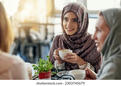 Friends, smile and Muslim women in coffee shop, bonding and talking together. Cafe, happy and Islamic girls, group or people chatting, conversation and discussion for social meeting in restaurant. - Powered by Shutterstock