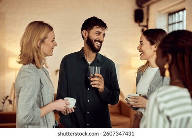 Friends smiling and talking while casually enjoying beverages together in a cozy setting.