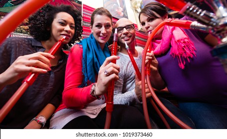 Friends Smoking A Hookah In Shisha Lounge Together