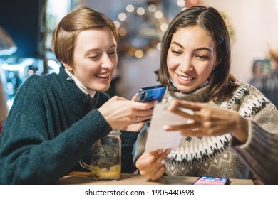 Friends split the bill using the app on their smartphone after a delicious dinner in a cafe.
