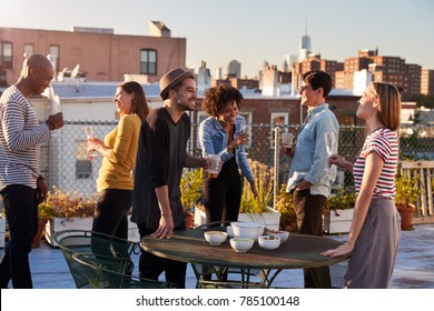 Friends Stand Talking At A Party On A New York Rooftop