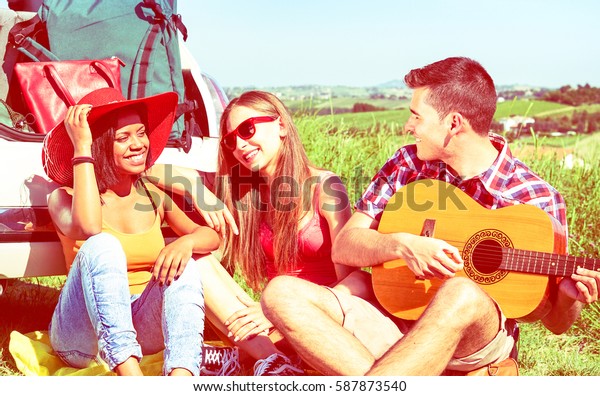 Friends summer camp with guitar and car on countryside
background - Multiracial teens having fun with music relax on grass
field outdoors - Concept of friendship  with vintage filter focus
on male   