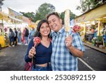 Friends take photos in the middle of the fair, hug each other and show off the snacks they have bought.