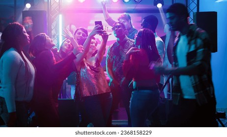 Friends taking pictures at disco party and having fun together on night out, dance event. Group of persons taking photos on phone, making fun memories at social celebration. Handheld shot. - Powered by Shutterstock