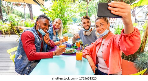 Friends Taking Selfie In A Bar Restaurant With Face Mask On In Coronavirus Time - Young People Having Fun With Drinks And Snacks Outside With New Rules After Virus Break
