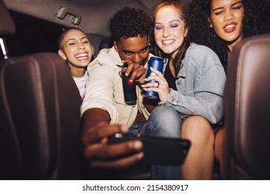 Friends Taking A Selfie Inside A Car At Night. Group Of Happy Young Friends Smiling Cheerfully While Posing For A Group Photo. Carefree Friends Taking A Ride Home After A Party.