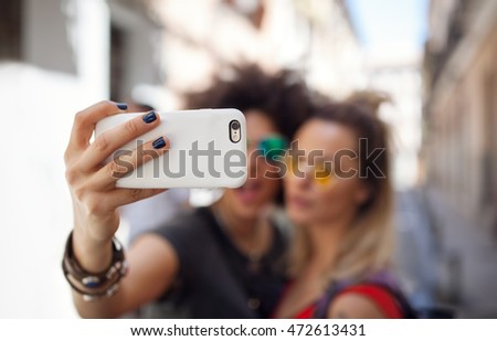 friends taking selfie together on summertime on street,shallow depth of field, focus on the smartphone