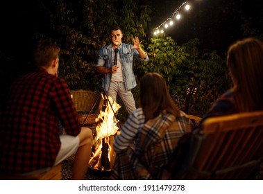 Friends tell scary stories by the bonfire, camping