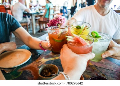 Friends Toasting, Saying Cheers Holding Tropical Blended Fruit Margaritas.  Watermelon And Passionfruit Drinks.